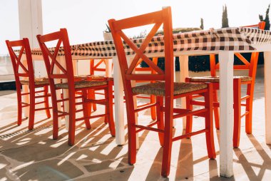  Gün batımında kafede kırmızı Yunan tarzı sandalyeler.