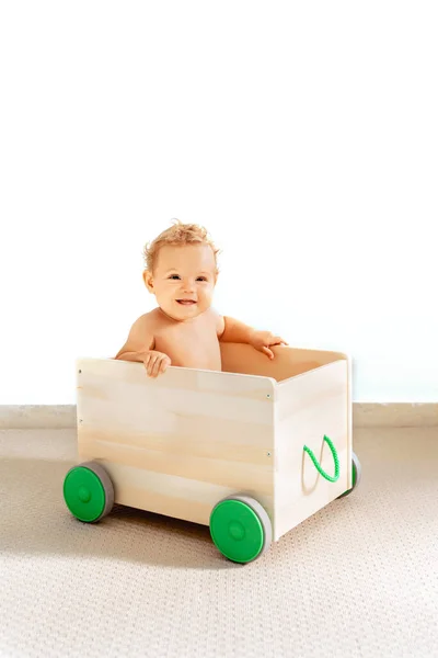 Bebé niña en una caja de juguetes sobre un fondo blanco, aislado. — Foto de Stock