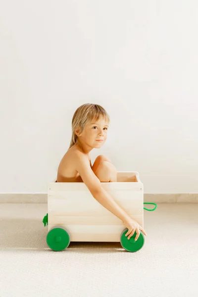 Niño en una caja de juguetes sobre un fondo blanco . — Foto de Stock