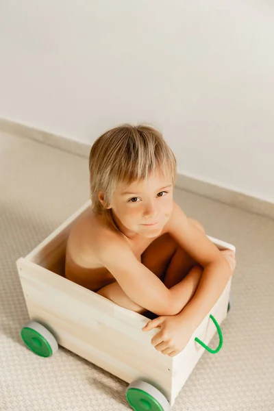 Niño en una caja de juguetes sobre un fondo blanco . — Foto de Stock