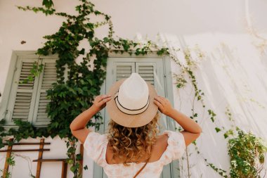 Sokaktaki saksıların arkasında şapkalı bir kız..