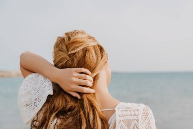 Kumsalda kızıl uzun saçlı gelin. Sırtında duruyorum.