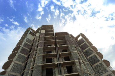 Mavi gökyüzünün arka planında yapım aşamasındaki çok katlı bir bina ve vinç.