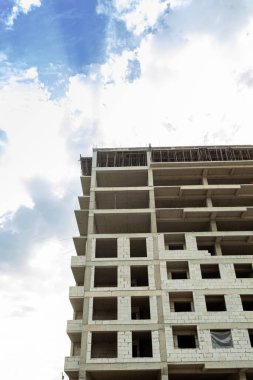 Mavi gökyüzünün arka planında yapım aşamasındaki çok katlı bir bina ve vinç.