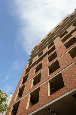 Mavi gökyüzünün arka planında yapım aşamasındaki çok katlı bir bina ve vinç.