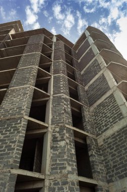 Mavi gökyüzünün arka planında yapım aşamasındaki çok katlı bir bina ve vinç.