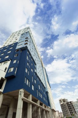 Mavi gökyüzünün arka planında yapım aşamasındaki çok katlı bir bina ve vinç.