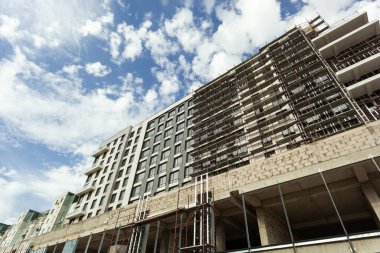 Mavi gökyüzünün arka planında yapım aşamasındaki çok katlı bir bina ve vinç.