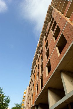 Mavi gökyüzünün arka planında yapım aşamasındaki çok katlı bir bina ve vinç.