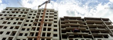 Mavi gökyüzünün arka planında inşaat halindeki çok katlı bir bina ve vinç manzarası