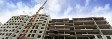 Mavi gökyüzünün arka planında inşaat halindeki çok katlı bir bina ve vinç manzarası