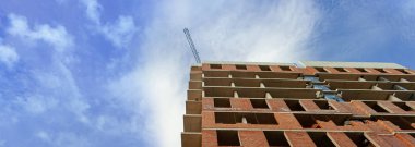 Mavi gökyüzünün arka planında inşaat halindeki çok katlı bir bina ve vinç manzarası