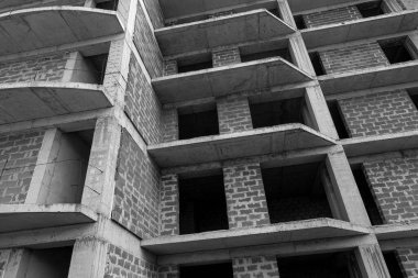 Mavi gökyüzünün arka planında yapım aşamasında olan çok katlı bir binanın siyah beyaz fotoğrafı.