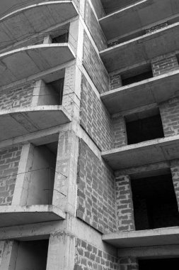 Mavi gökyüzünün arka planında yapım aşamasında olan çok katlı bir binanın siyah beyaz fotoğrafı.