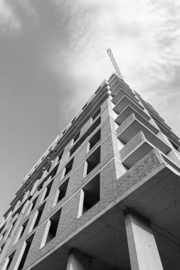 Mavi gökyüzünün arka planında yapım aşamasında olan çok katlı bir binanın siyah beyaz fotoğrafı.