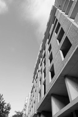 Mavi gökyüzünün arka planında yapım aşamasında olan çok katlı bir binanın siyah beyaz fotoğrafı.