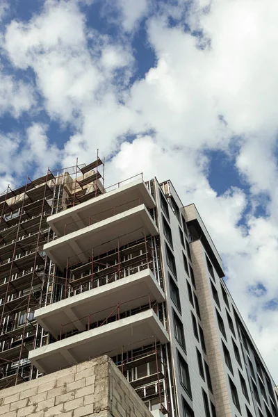 Multi-storey residential building under construction and crane on a background of blue sky