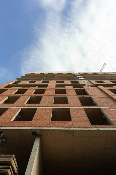 Mavi gökyüzünün arka planında yapım aşamasındaki çok katlı bir bina ve vinç.