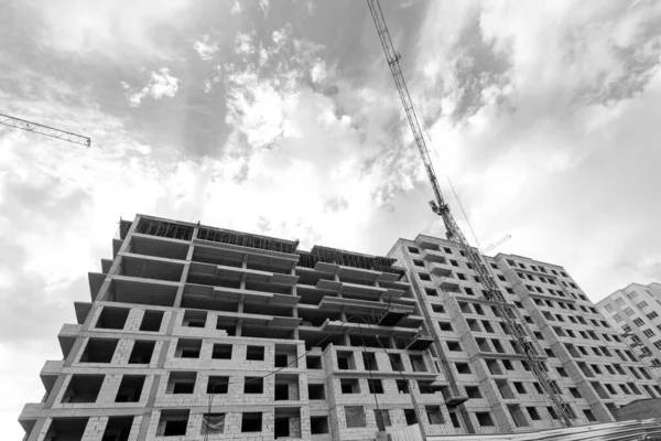 青空を背景に建設中の複数階建ての住宅やクレーンの白と黒の写真 — ストック写真