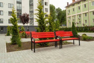 Yeni bir yerleşim yerinin avlusundaki güzel kırmızı ahşap bank.