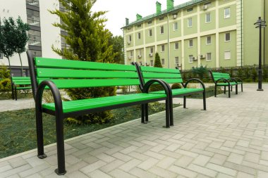 Yeni bir yerleşim yerinin avlusunda güzel yeşil ahşap bir bank.