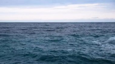 Dalgalar denizde ve gökyüzünde Uzaktaki bulutlarla