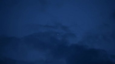 Bulutlar alacakaranlıkta yalnız bir yıldızın arka planında süzülür ve bulutların arkasında kaybolur.
