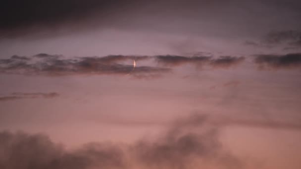 深紅の夕日を背景にした若い三日月 浮いている雲の間の月は バラ色の日没で沈んでいます 日没時に雲が浮かぶ — ストック動画