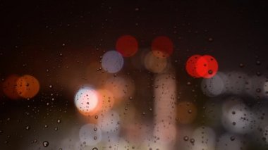 Geceleri bardaktan yağmur damlaları akıyor. Bokeh 'in arka planındaki cama yağmur damlaları damlıyor. Geceleri pencerenin dışında yağmur yağar