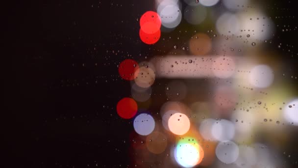 雨滴在夜里从玻璃杯里流下来 玻璃杯上的雨滴在Bokeh的背景上 晚上从窗户外面下雨 — 图库视频影像
