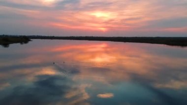 İki ördek güzel bir gün batımında nehirde birlikte yüzer ve bazen martılar uçar..