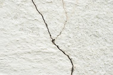 Beyaz beton duvardaki çatlakların dokusu.
