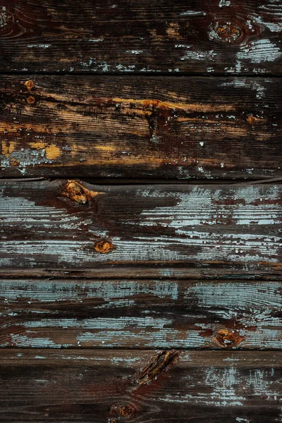 The texture of an old wooden wall of boards with peeling blue paint