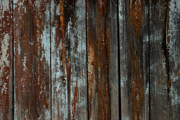 The texture of an old wooden wall of boards with peeling blue paint