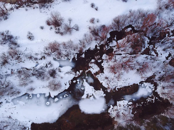 The forest and the frozen river with thawed patches appeared in the spring, when there is still snow in Russia from the height of the quadrocopter