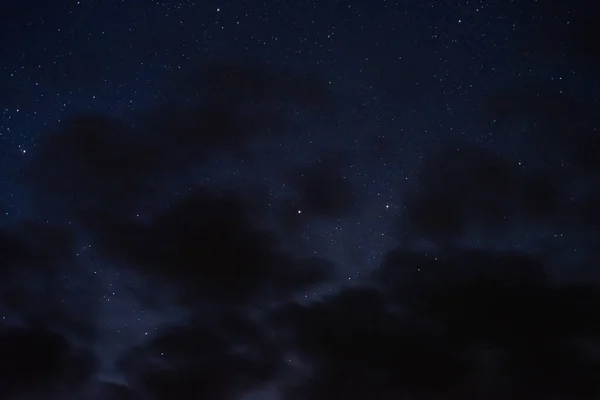 Gece gökyüzündeki yıldızlar bulutlar arasında