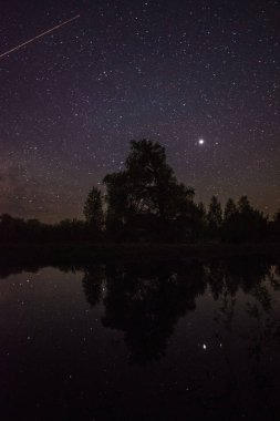 Geceleri göldeki yıldızların ve ağaçların yansıması.