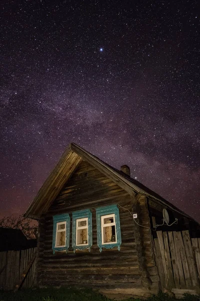 Geceleri bir Rus köyünde samanyolu ve yıldızlı gökyüzüne karşı tipik bir ev.