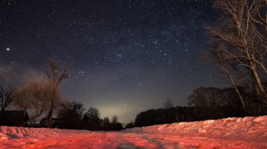 Yol kışı, köyde yıldızlı bir gecede. Ağaçların orada..