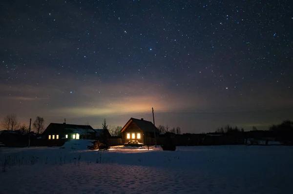 Rus köyündeki evler. Kış, soğuk bir gece. Evlerin çatıları üzerinde yıldızlı gökyüzü.