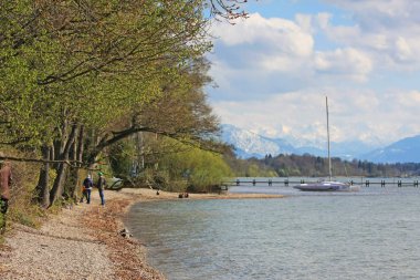 Starnberg Gölü 'nde teknesi olan rıhtım. Arkasında karlı tepeler var.