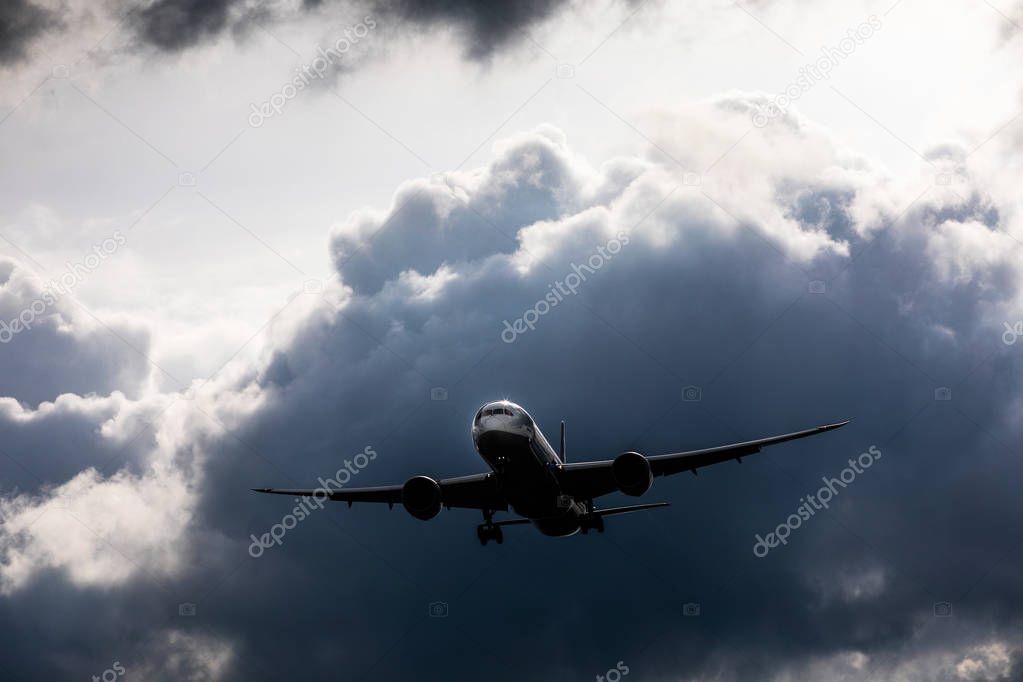 Heavy aircraft fly in front of rain cloud in sunny day