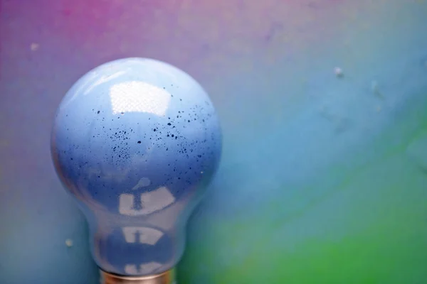 カラフルな背景に青い電球 — ストック写真