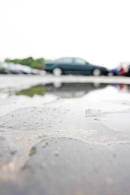 Arka planda bulanık arabalar olan ıslak kaldırım taşı yüzeyine yakın plan.