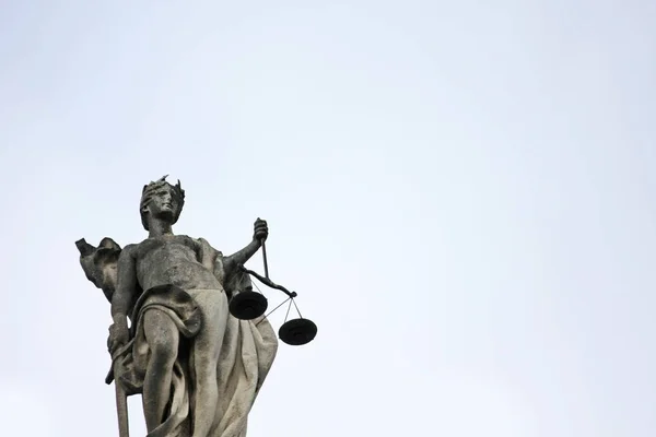 Sculpture of justice holding scale in hand