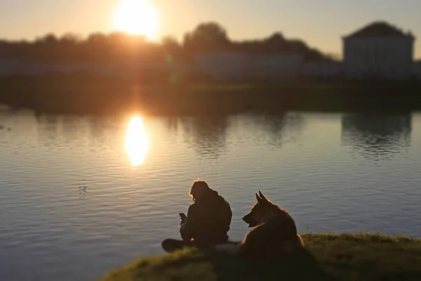 Mann Sitzt Sonnenuntergang Mit Hund See — Stockfoto