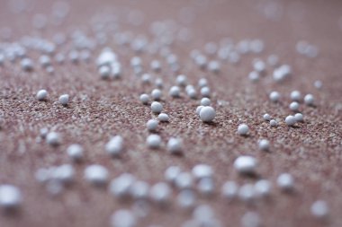 Kahverengi halıya dağılmış beyaz taşlar.