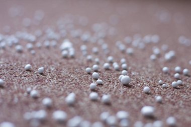 Kahverengi halıya dağılmış beyaz taşlar.