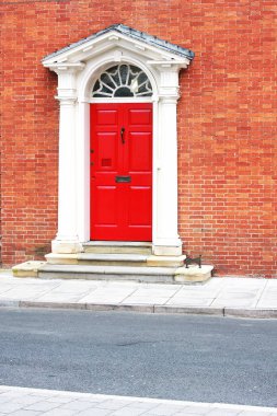 kırmızı kapı beyaz klasik çerçeve sütunlar ve tuğla duvar