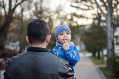 Düşünen çocuk babasının kollarında: Düşünceli bir çocuğun portresi, çenesine bir parmak konmuş ve yukarı izlerken, babam onu cadde boyunca taşıyor. Komik tefekkür ve seçim (seçim) kavramı